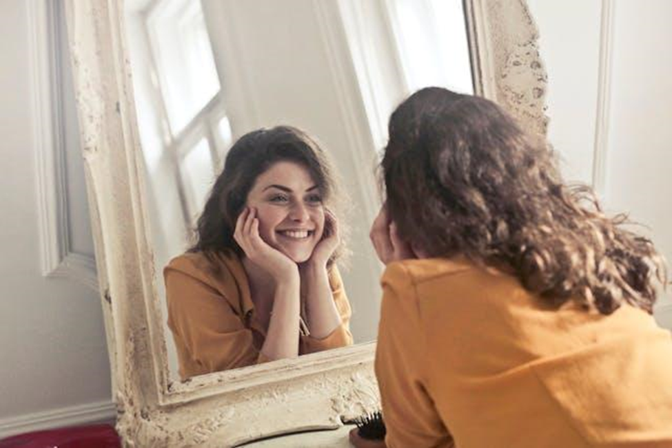 A woman looking at her reflection in the mirror