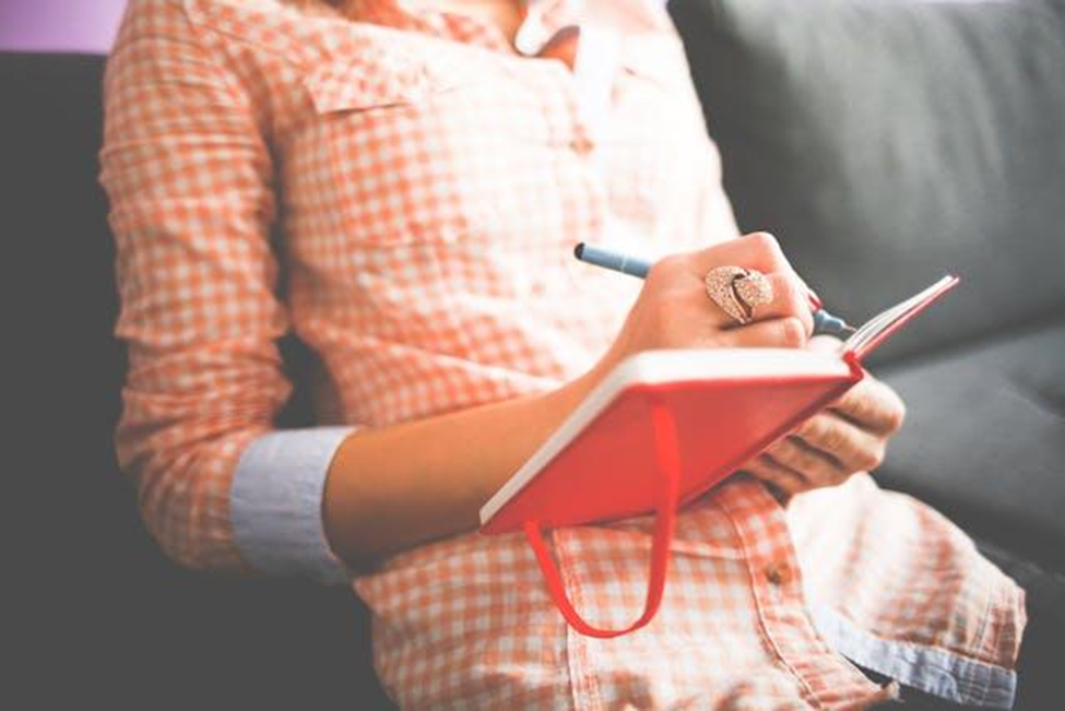 A woman writing in a red journal