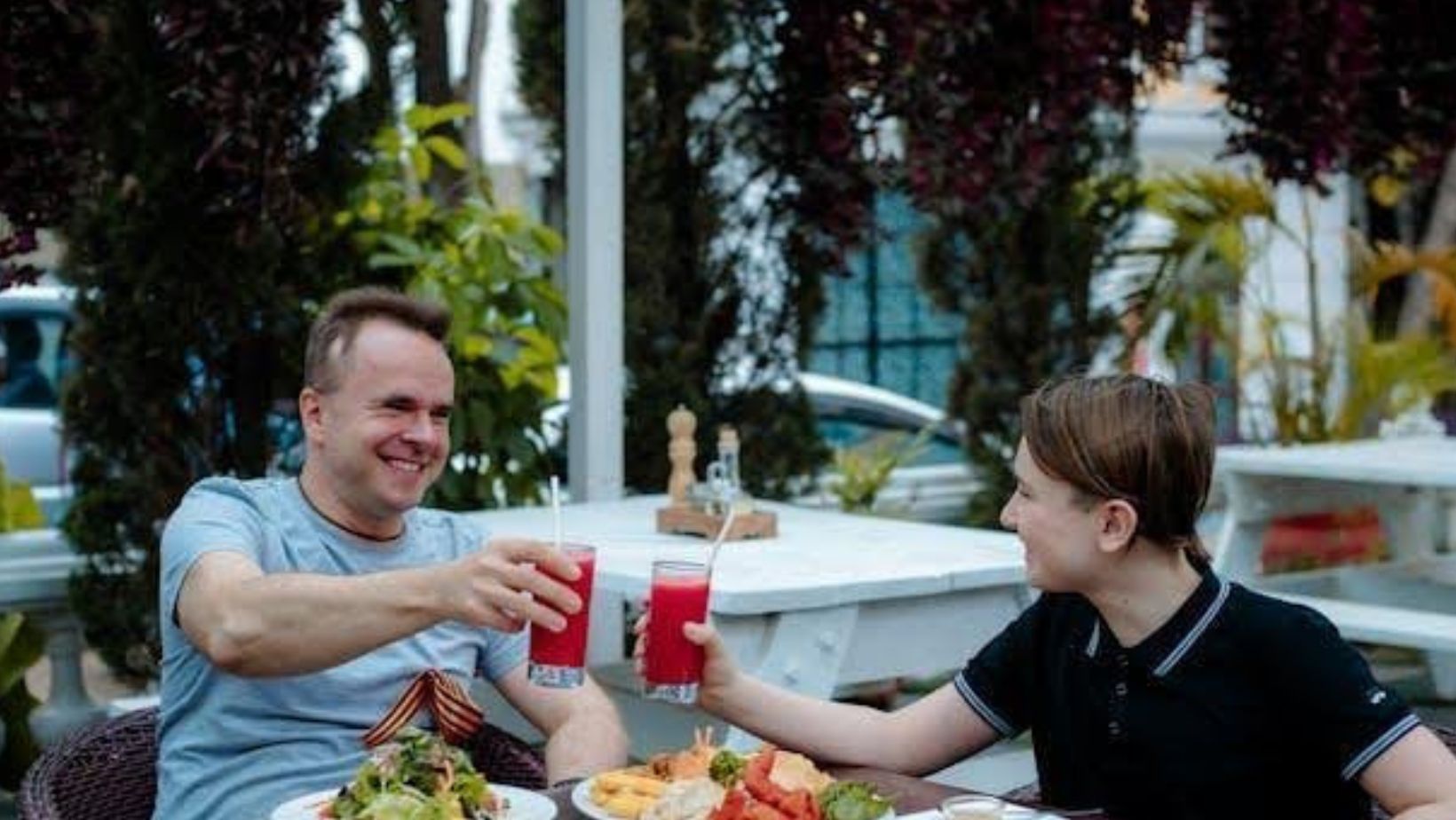 A father and son enjoying lunch and drinks together.
